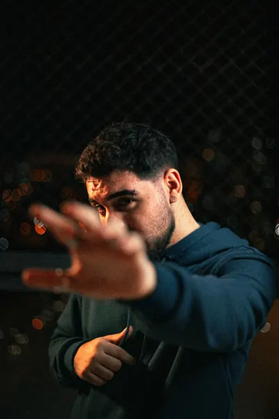 Hand raised to camera, night bokeh